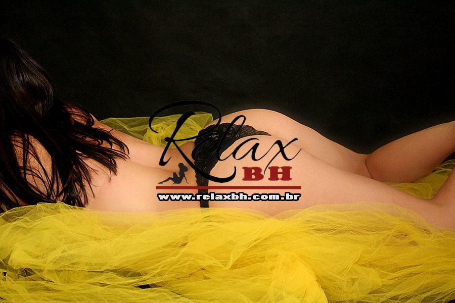 Back view of a person lying on yellow tulle fabric, wearing black lace lingerie, with a watermark reading 'Relax BH' and the site URL across the image